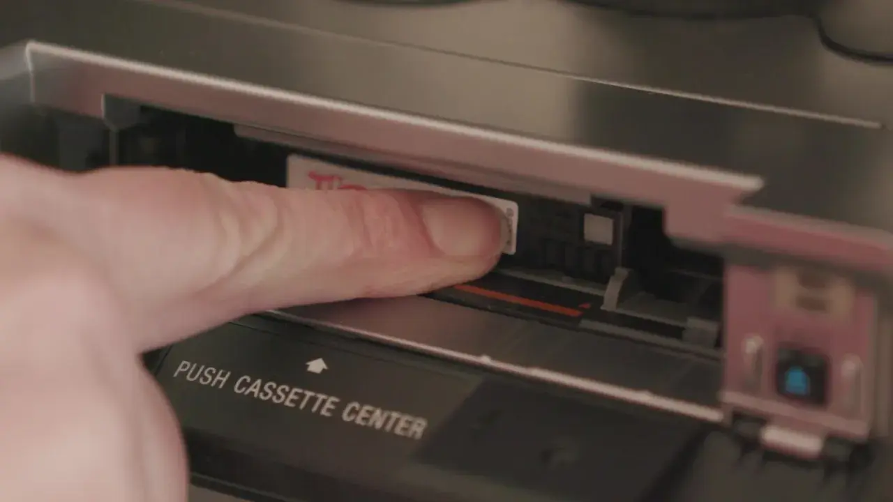 Dito, un dito inserisce una cassetta Hi8 in un videoregistratore, un pezzo di storia delle fotografie.
