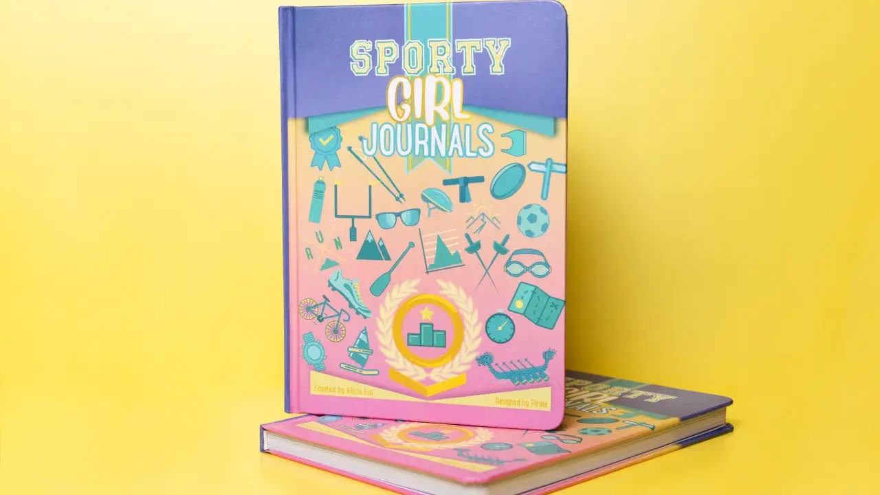 Come fotografare un libro: due quaderni "Sporty Girl Journals" con copertine colorate e illustrazioni sportive su sfondo giallo.