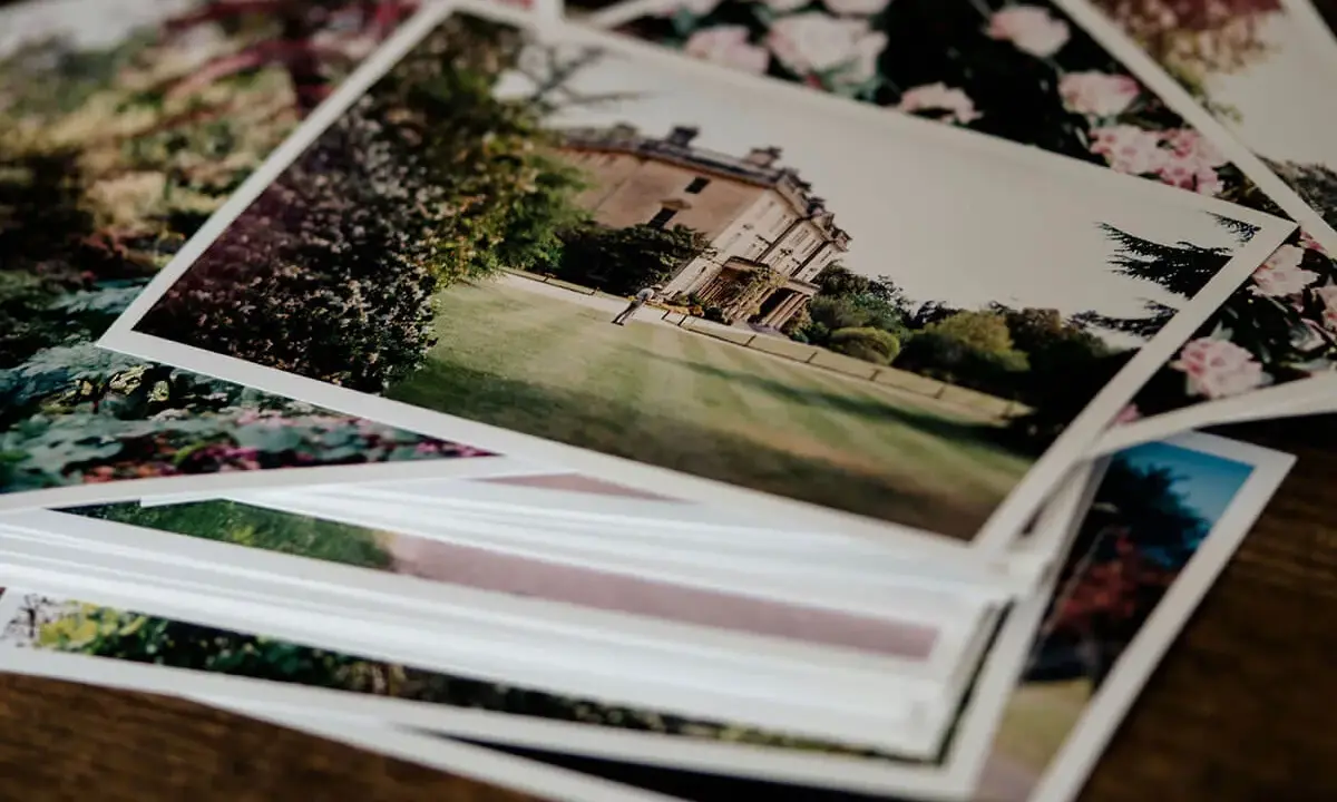 Pile di foto stampate su carta matte, con un palazzo e fiori. Il loro significato è legato ai ricordi preziosi.