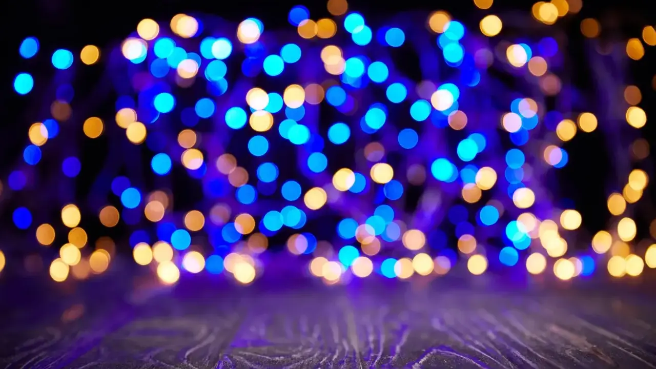 Luci sfocate blu e dorate creano un'atmosfera magica su uno sfondo scuro e un piano in legno viola.