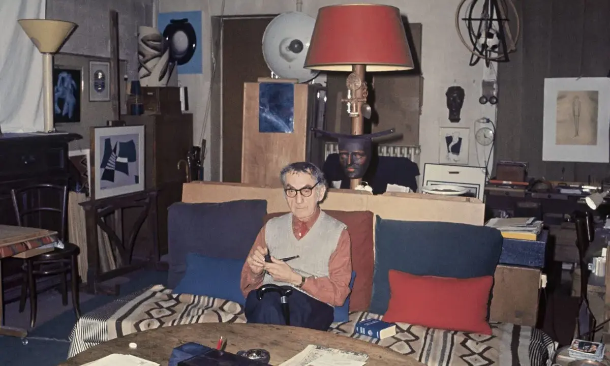 Man Ray nel suo studio, circondato da opere fotografiche e oggetti d'arte.