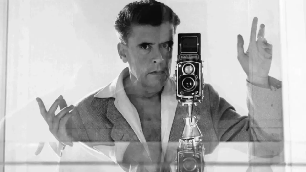 Herbert List si scatta un autoritratto con la sua Rolleiflex, un'immagine iconica che cattura il suo sguardo intenso e le mani in gesto.