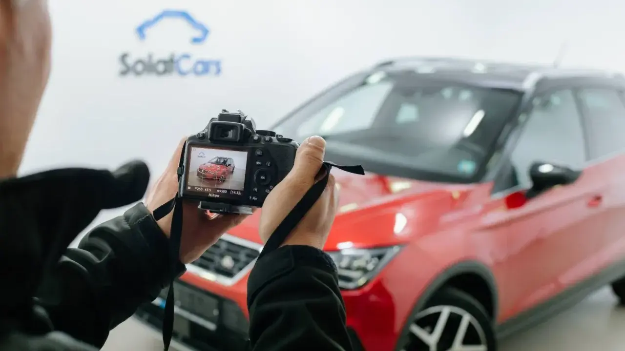 Persona che scatta foto a un'auto rossa ferma, con la telecamera che mostra l'anteprima.