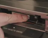 Dito, un dito inserisce una cassetta Hi8 in un videoregistratore, un pezzo di storia delle fotografie.