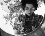 La fotografa famosa si riflette in uno specchio, impugnando la sua macchina fotografica.