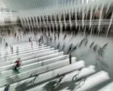 Persone in movimento in una grande hall moderna, con un forte effetto mosso che crea un senso di dinamismo e velocità.
