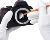 Mani guantate eseguono la pulizia sensore reflex con uno strumento apposito per rimuovere polvere e sporco, garantendo immagini nitide.