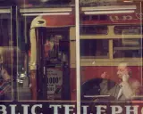 Un uomo al telefono, riflesso su una vetrina, evoca l'atmosfera urbana di Saul Leiter.