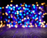 Luci sfocate blu e dorate creano un'atmosfera magica su uno sfondo scuro e un piano in legno viola.