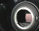 Dettaglio di una fotocamera con attacco obiettivo aperto, mostrando i contatti per i sensori digitali.