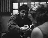 Un uomo con barba e baffi, forse Che Guevara, accende una sigaretta, catturato da rene burri.