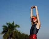 Modella con occhiali da sci arancioni e gonna a paillettes rosse, in un servizio di fotografi di moda all'aperto.