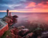 Faro su scogliera al tramonto, con cielo infuocato e mare calmo. Un filtro polarizzatore a cosa serve? A rendere i colori più vividi e il cielo più profondo.