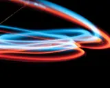 Linee luminose blu e arancioni danzano su sfondo nero, un'esplosione di **light painting** astratto.