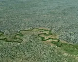 Un fiume serpeggia in un paesaggio arido, un'immagine che evoca la sensibilità di Stephen Shore per la bellezza ordinaria.