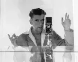 Herbert List si scatta un autoritratto con la sua Rolleiflex, un'immagine iconica che cattura il suo sguardo intenso e le mani in gesto.