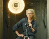 Annie Leibovitz foto: la celebre fotografa con la sua macchina fotografica, illuminata da un grande riflettore.