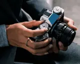 Mani che regolano i quadranti di una fotocamera, con un anello al dito. Immagine fotografica.