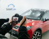 Persona che scatta foto a un'auto rossa ferma, con la telecamera che mostra l'anteprima.