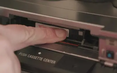 Dito, un dito inserisce una cassetta Hi8 in un videoregistratore, un pezzo di storia delle fotografie.