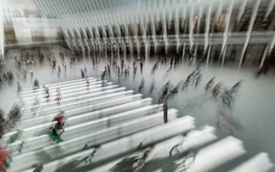 Persone in movimento in una grande hall moderna, con un forte effetto mosso che crea un senso di dinamismo e velocità.