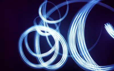 Light painting still life con fili di luce blu che danzano su sfondo scuro, creando un effetto etereo e astratto.