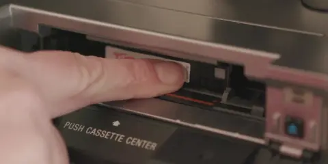 Dito, un dito inserisce una cassetta Hi8 in un videoregistratore, un pezzo di storia delle fotografie.
