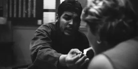 Un uomo con barba e baffi, forse Che Guevara, accende una sigaretta, catturato da rene burri.