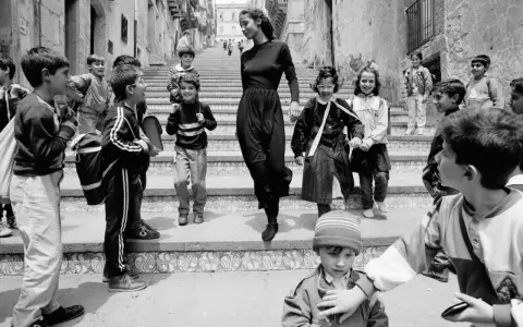 Bambini con zaini scendono una scalinata, accompagnati da una donna elegante. Un'istantanea che cattura la vivacità di queste fotografie famose.