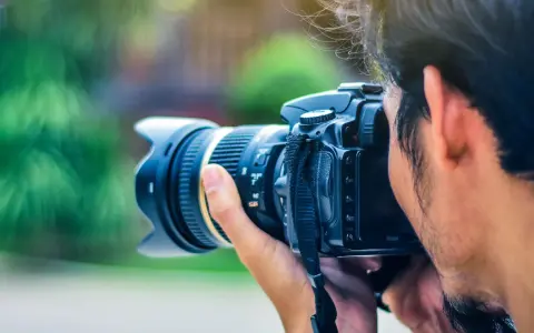 Un fotografo cattura un momento con la sua macchina fotografica reflex, il sole illumina i suoi capelli mossi.