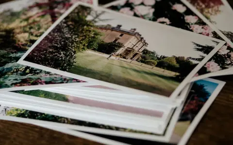 Pile di foto stampate su carta matte, con un palazzo e fiori. Il loro significato è legato ai ricordi preziosi.