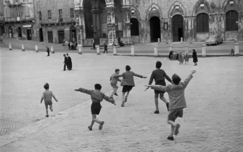 Bambini giocano in una piazza, un momento di street photography famosi.