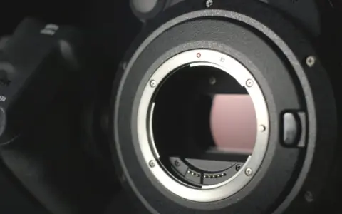 Dettaglio di una fotocamera con attacco obiettivo aperto, mostrando i contatti per i sensori digitali.