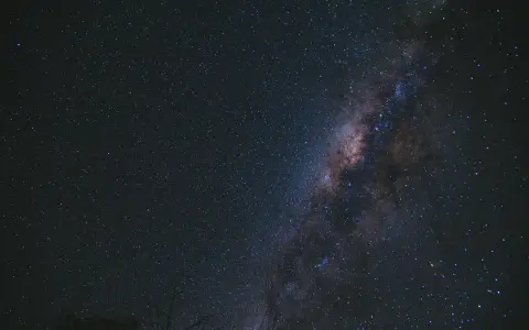 Una foto al cielo notturno, con la Via Lattea che brilla tra innumerevoli stelle.