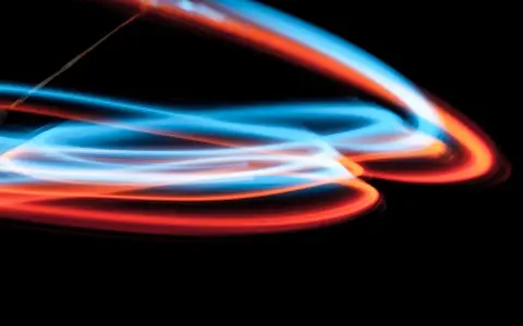 Linee luminose blu e arancioni danzano su sfondo nero, un'esplosione di **light painting** astratto.