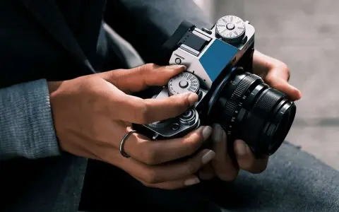 Mani che regolano i quadranti di una fotocamera, con un anello al dito. Immagine fotografica.