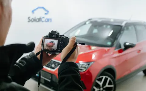 Persona che scatta foto a un'auto rossa ferma, con la telecamera che mostra l'anteprima.