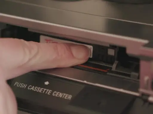 Dito, un dito inserisce una cassetta Hi8 in un videoregistratore, un pezzo di storia delle fotografie.
