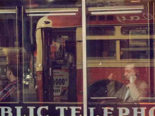 Un uomo al telefono, riflesso su una vetrina, evoca l'atmosfera urbana di Saul Leiter.
