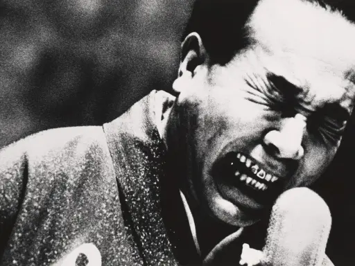 Un uomo con gli occhi chiusi e la bocca spalancata in un grido, un'espressione intensa catturata da Daidō Moriyama.