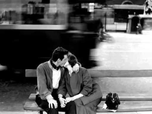 Un bacio rubato tra le opere di Robert Doisneau, un momento sospeso nel tempo con un tram sfocato sullo sfondo.