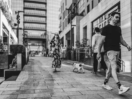 Un uomo cammina con il suo cane, un'istantanea da street photographer in una via moderna.