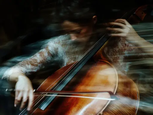 Donna suona il violoncello con un effetto mosso, quasi etereo. Un esempio di come fare foto mosse con iPhone per un risultato artistico.