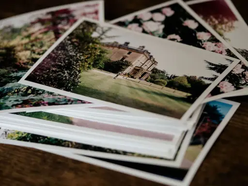 Pile di foto stampate su carta matte, con un palazzo e fiori. Il loro significato è legato ai ricordi preziosi.