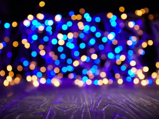 Luci sfocate blu e dorate creano un'atmosfera magica su uno sfondo scuro e un piano in legno viola.