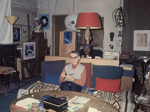 Man Ray nel suo studio, circondato da opere fotografiche e oggetti d'arte.