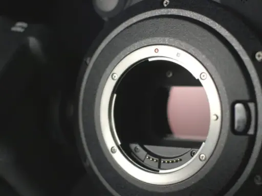 Dettaglio di una fotocamera con attacco obiettivo aperto, mostrando i contatti per i sensori digitali.