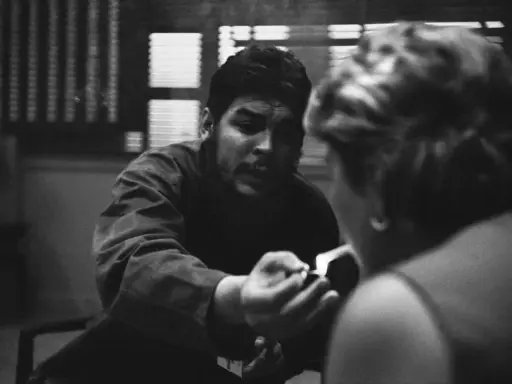 Un uomo con barba e baffi, forse Che Guevara, accende una sigaretta, catturato da rene burri.