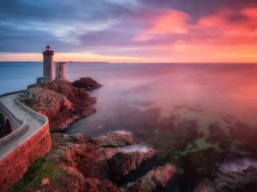 Faro su scogliera al tramonto, con cielo infuocato e mare calmo. Un filtro polarizzatore a cosa serve? A rendere i colori più vividi e il cielo più profondo.
