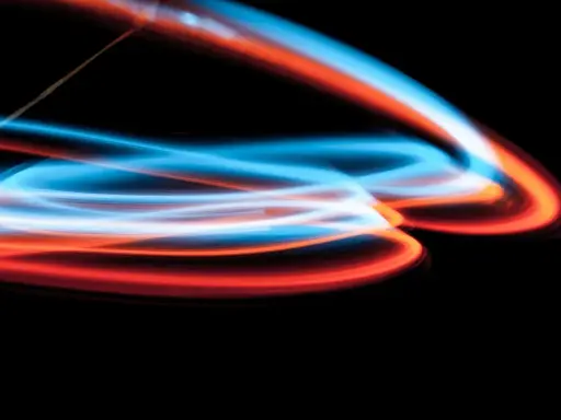 Linee luminose blu e arancioni danzano su sfondo nero, un'esplosione di **light painting** astratto.